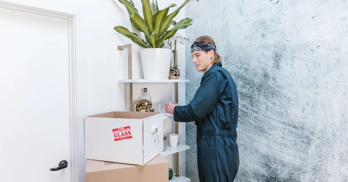 Man in uniform arranging home items with cardboard boxes ready for moving.