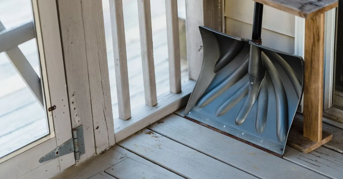 From above of wooden shovel with handle placed on floor of terrace near door