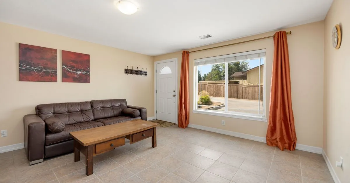 Bright living room with leather sofa, wooden coffee table, and large window view.